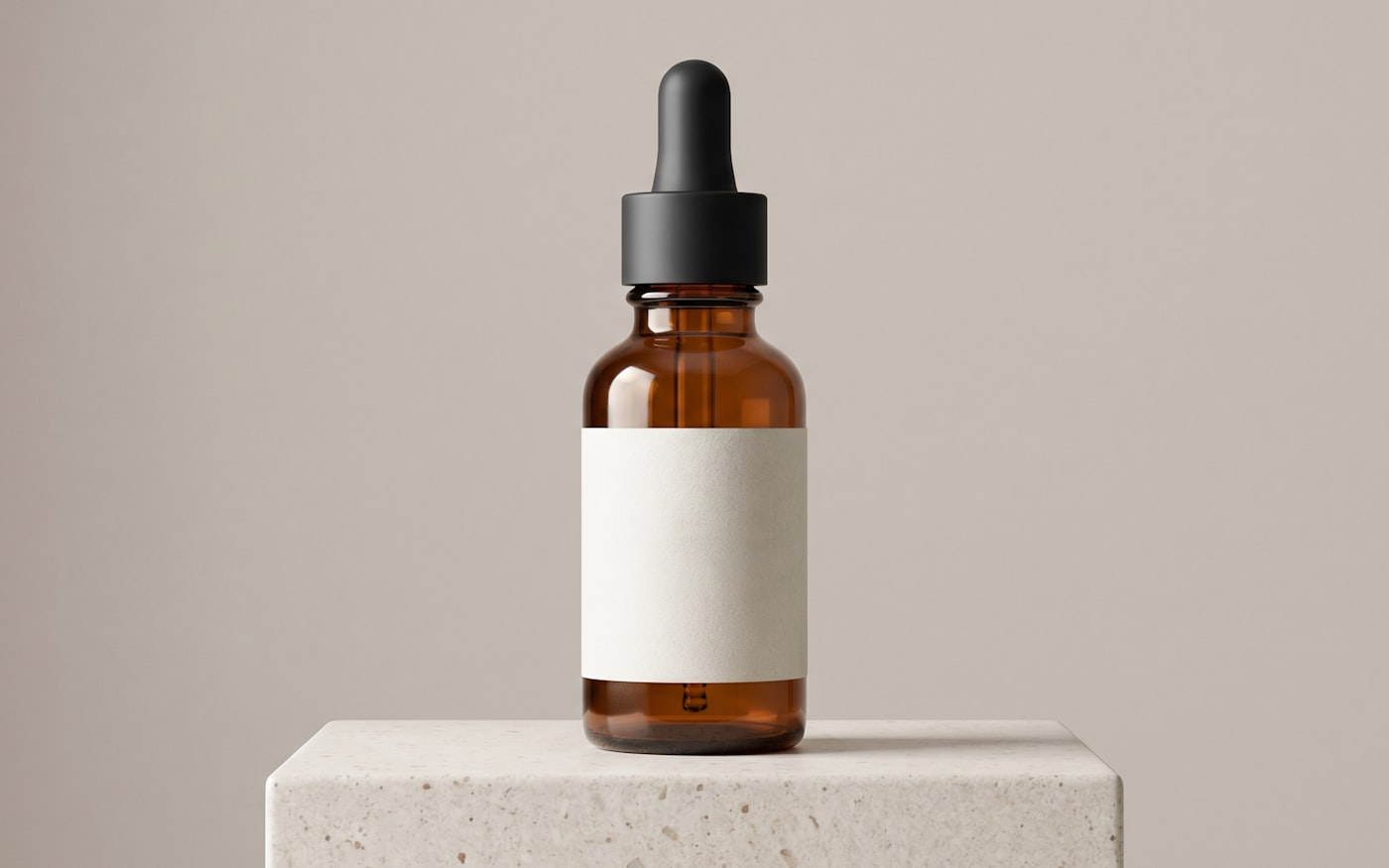 An amber serum dropper bottle standing on a stone plinth